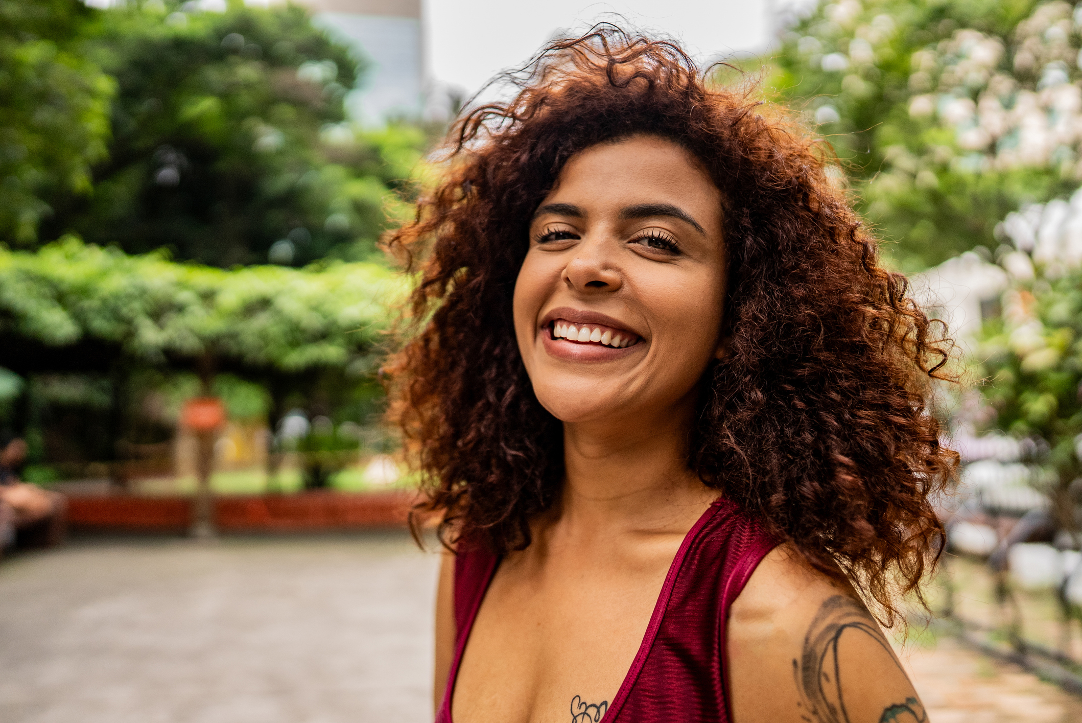 Smiling tattooed woman with curly hair outdoors