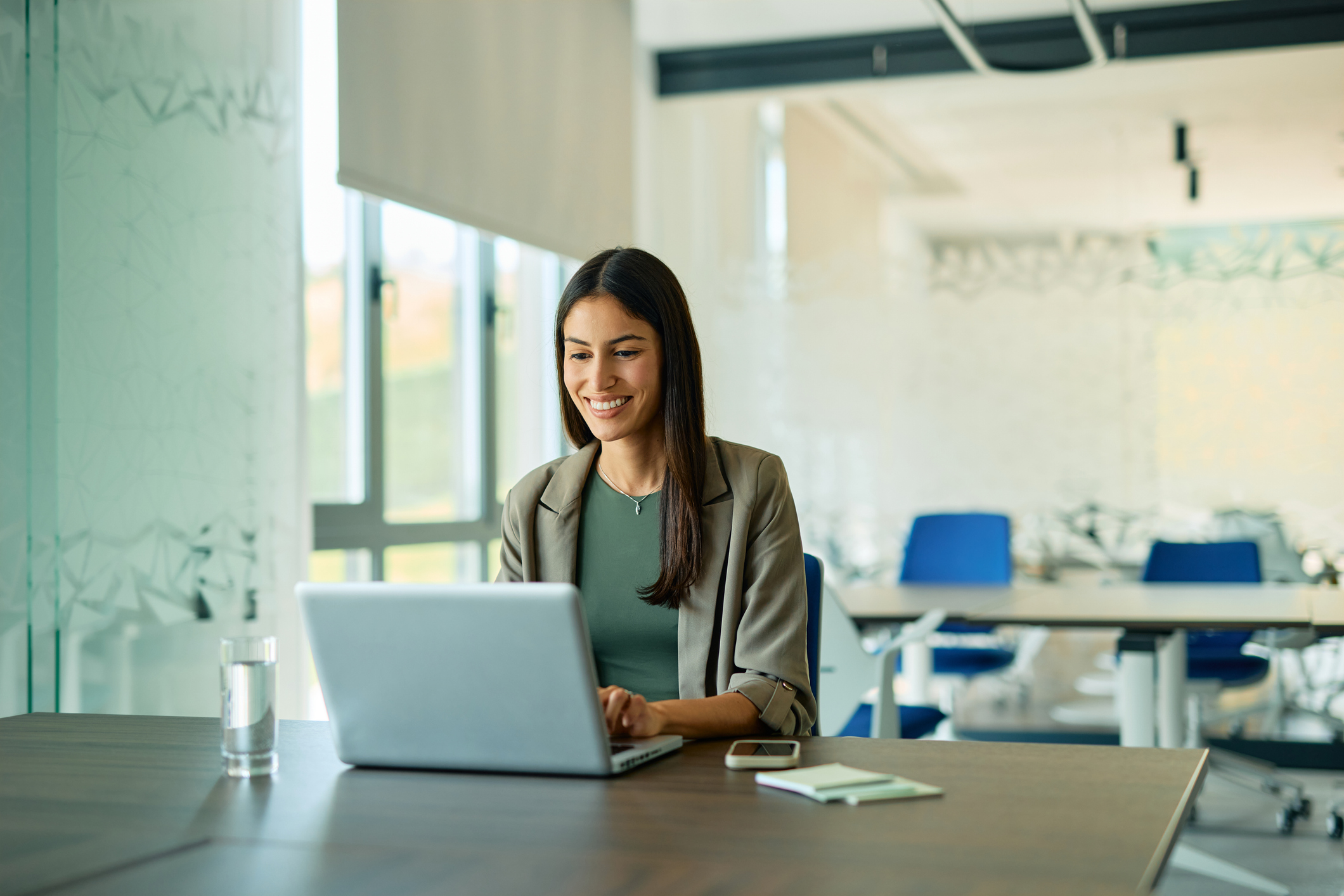 Smiling businesswoman working on laptop in office
