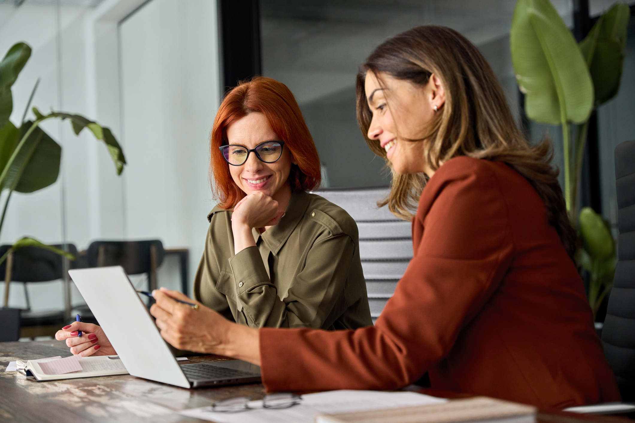 Two women collaborating over laptop in office